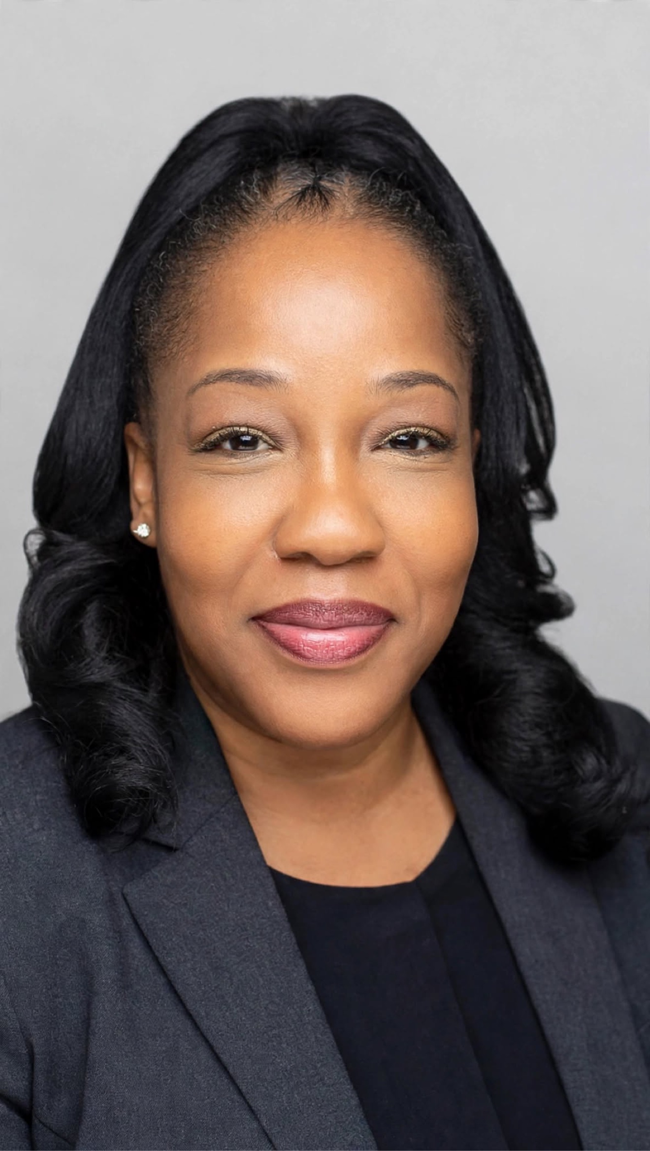 Sharlita in a gray blazer, smiling against a light gray background